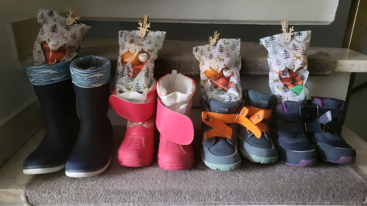 Tagesmütter Augsburg-Land e.V. - Kita-Trägerverband - Vier Paar Kinderwinterstiefel stehen auf einer Treppe. An jedem Paar hängt ein gemusterter Stoffbeutel, der mit einer Wäscheklammer aus Holz befestigt ist.